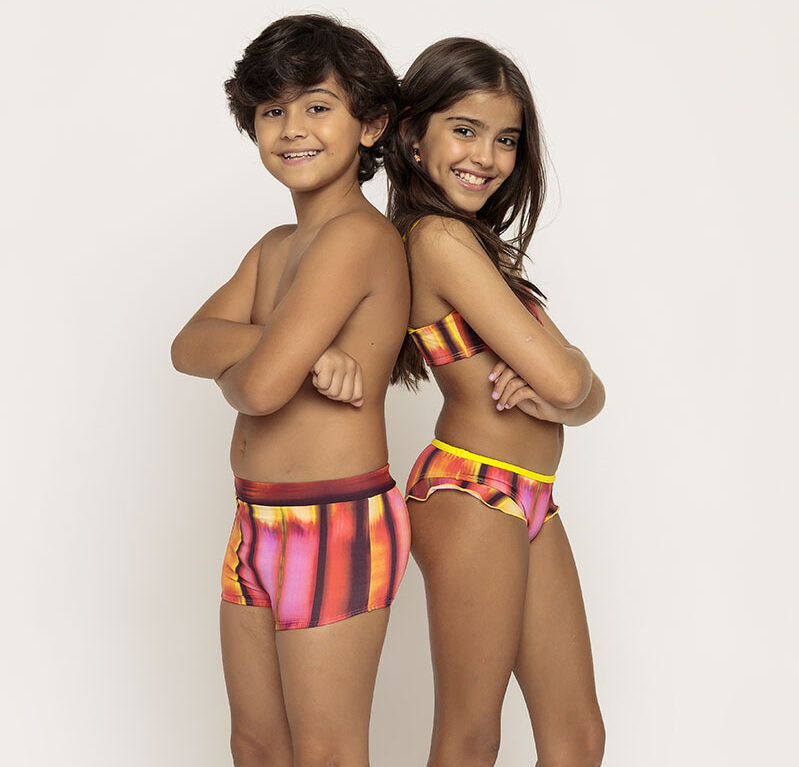um menino usando uma sunga colorida de costas com uma menina usando um biquini colorido na mesma estampa